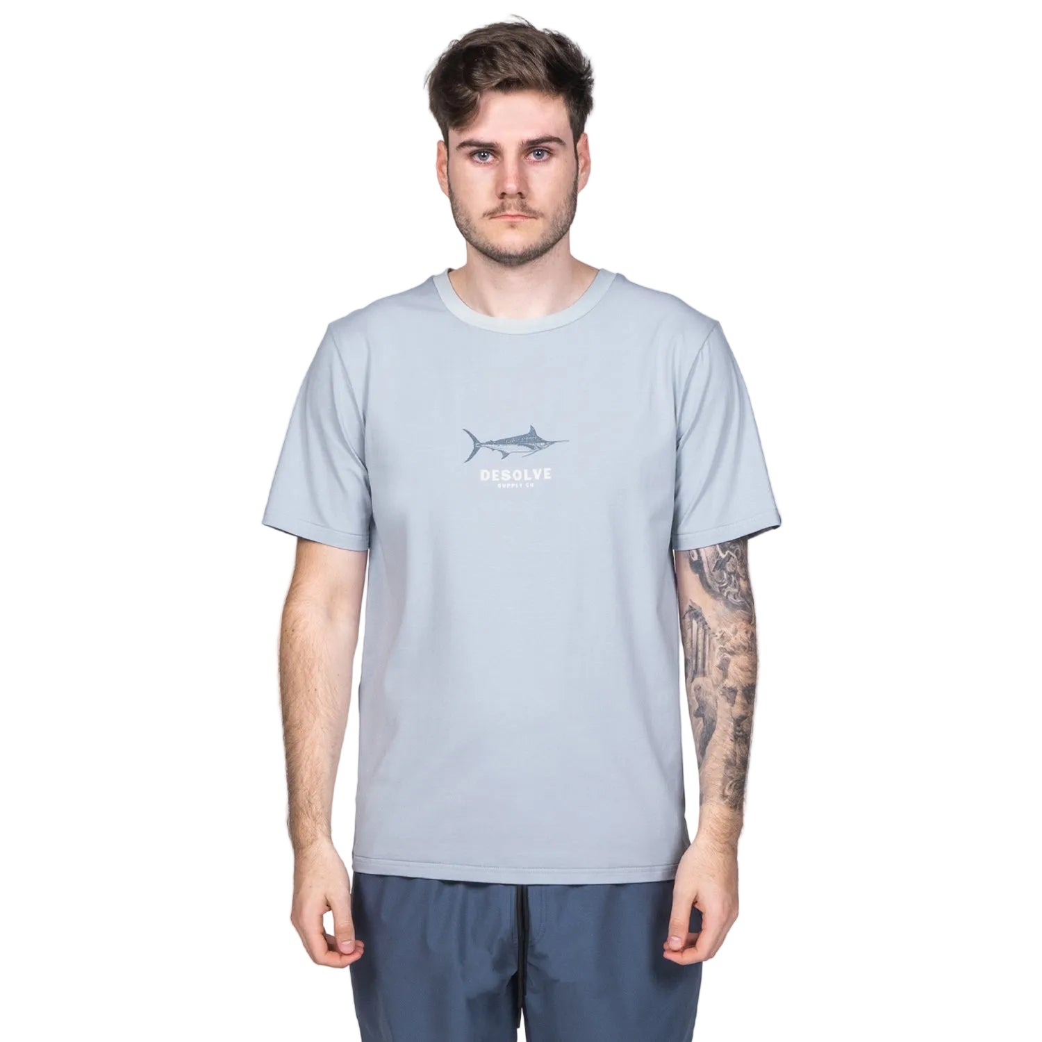 A male model wearing a light gray t-shirt with a fish graphic print, paired with dark shorts.