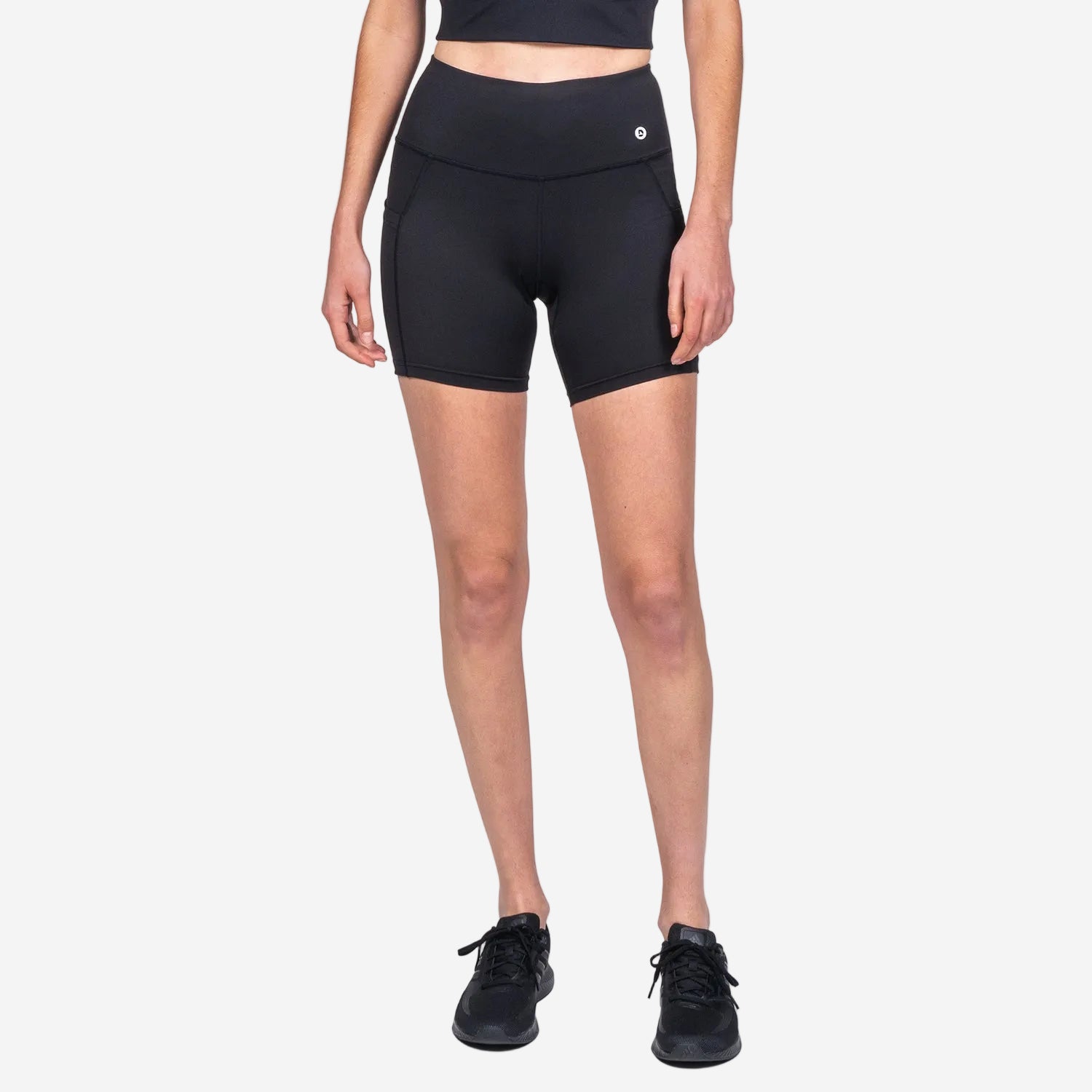 A pair of black, midi-length biker shorts with a high waist and internal waist drawstring. The shorts feature flatlock seams and a side pocket.
