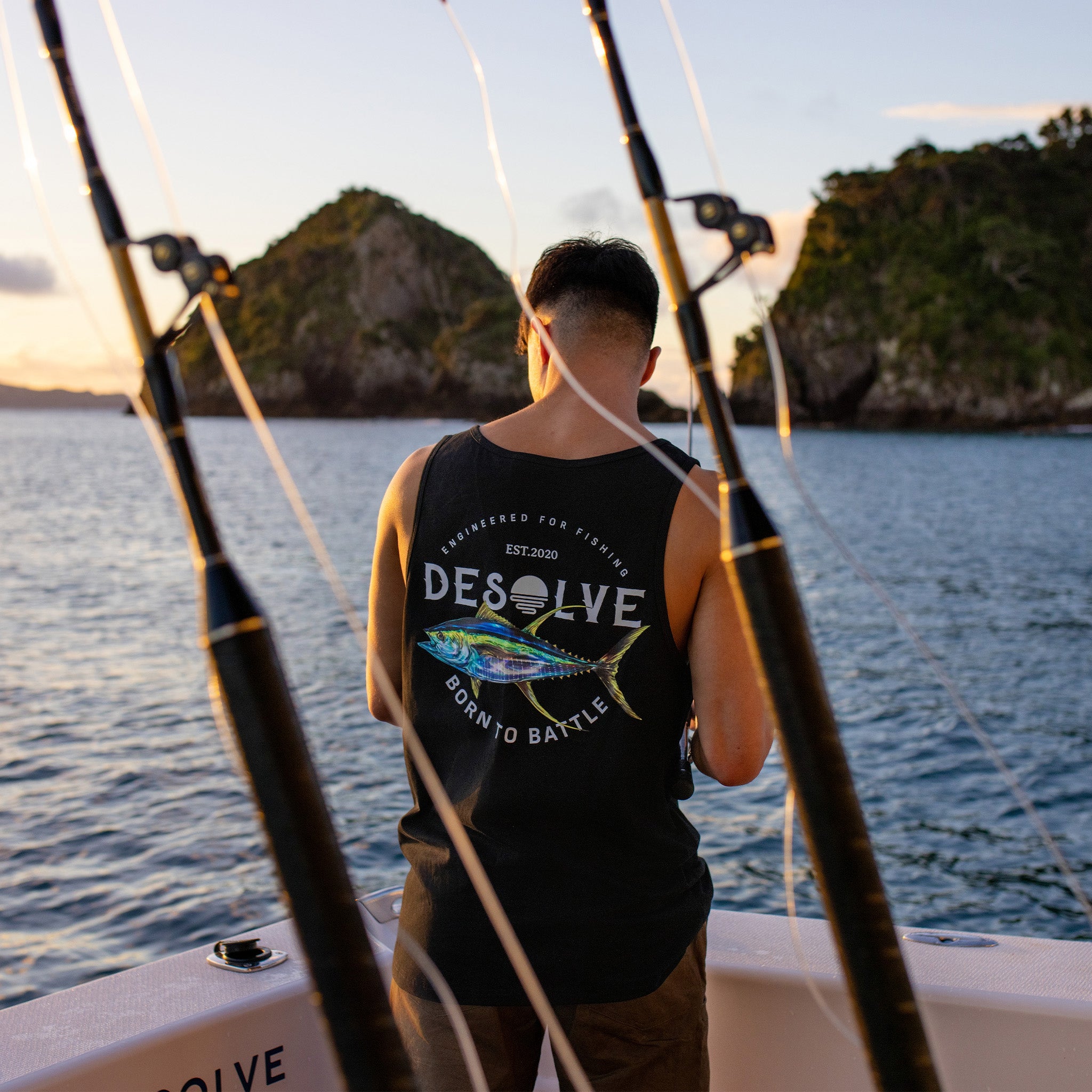 Person on a boat holding fishing rods with a scenic background